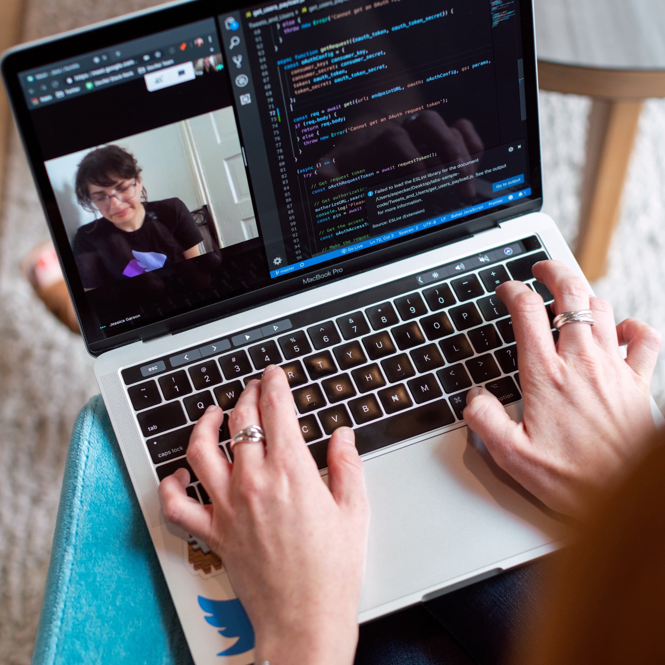 Person typing code on a MacBook Pro whilst having a video call.