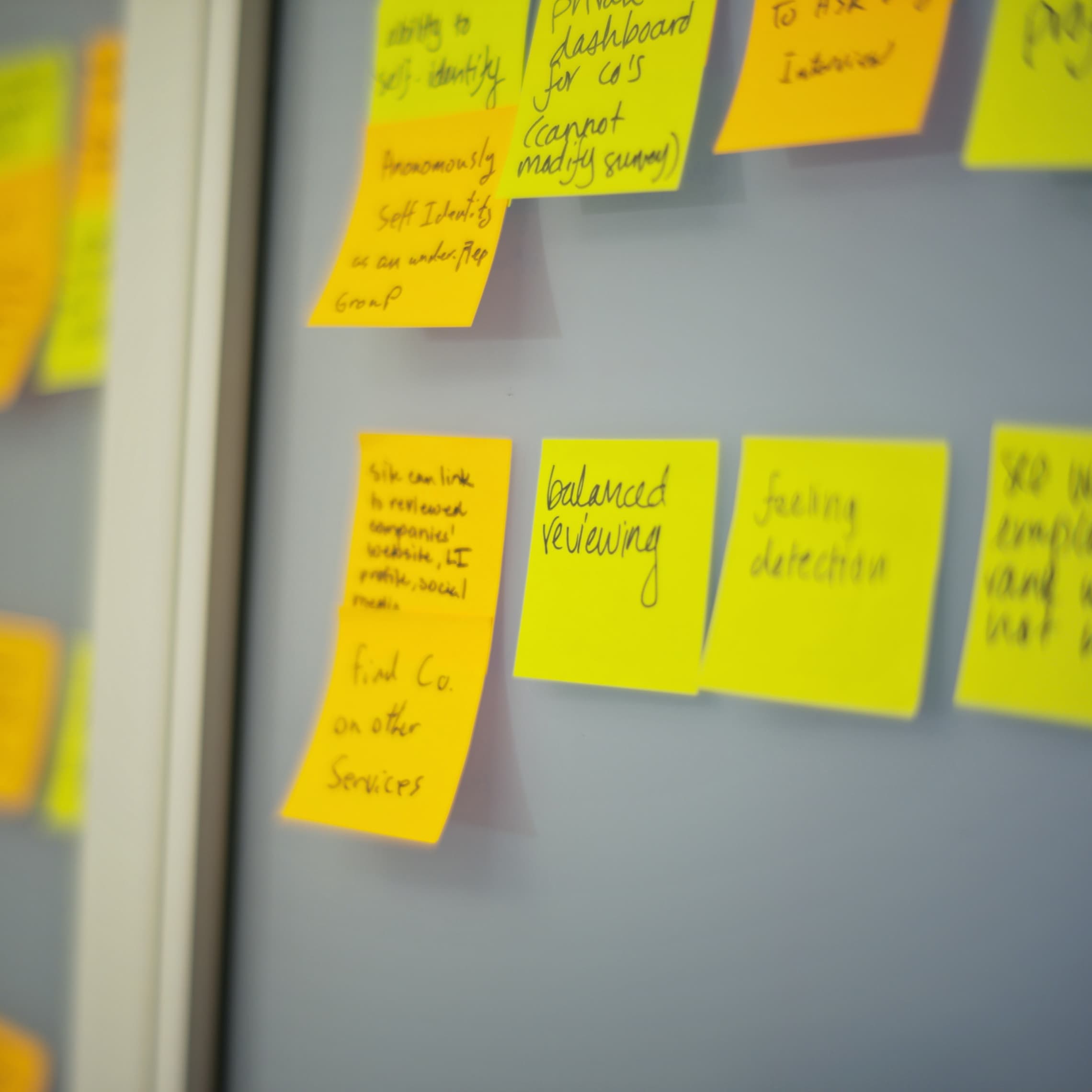 Selective focus photography of yellow and orange post-it notes on wall.