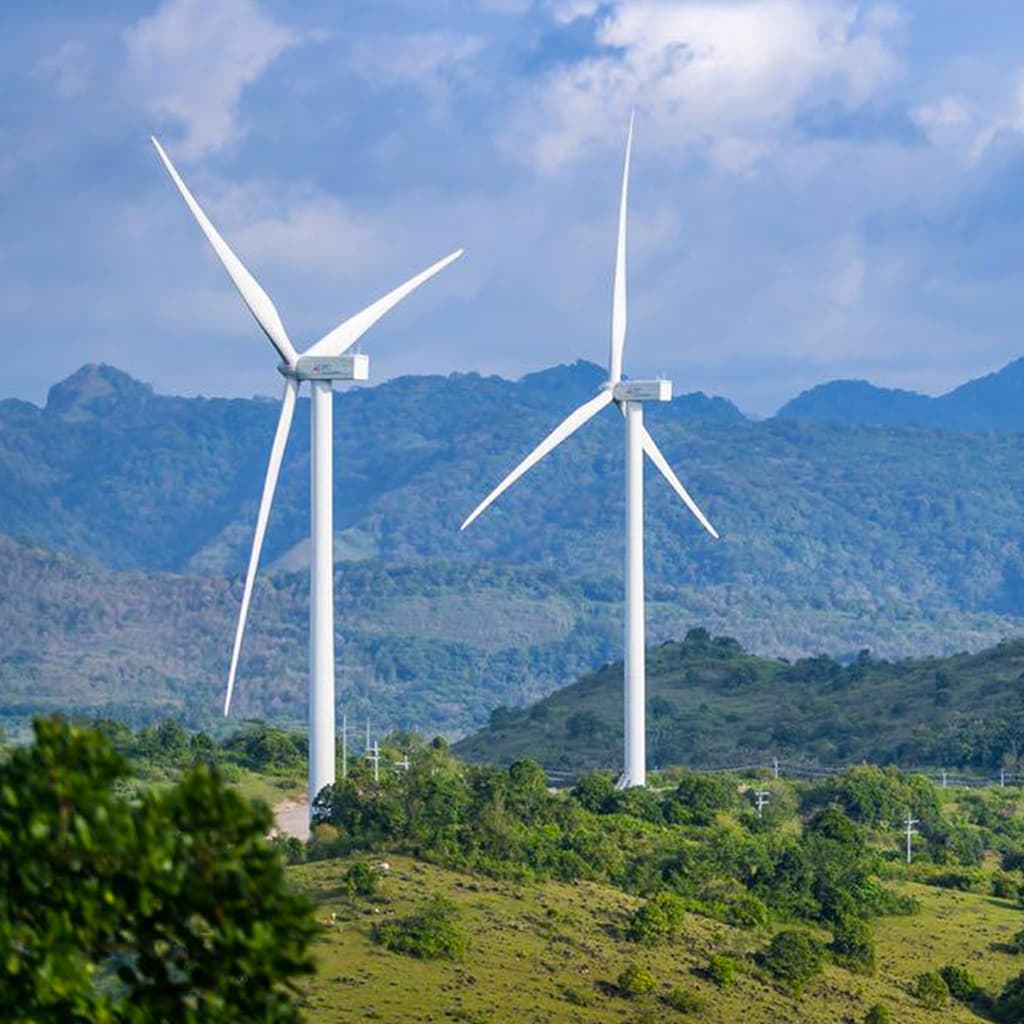 A view over a green, hilly landscape showing two power-generating windmills.